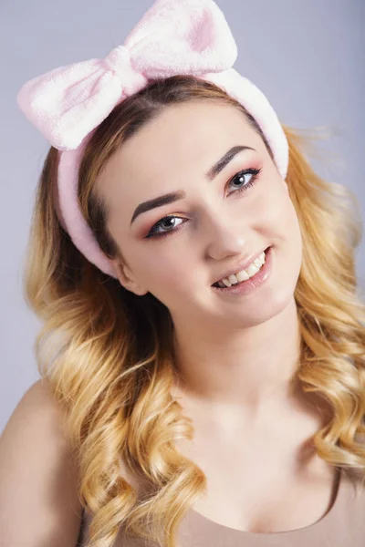 soft studio portrait of a happy young woman with fluffy soft hoop on head that picks hair, fresh girl face with make up, the concept of natural beauty, body care, cosmetics