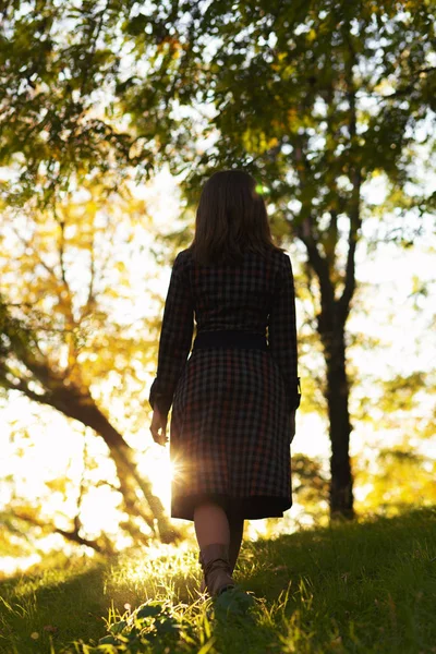 Silueta de una joven mujer ascendiendo en la colina al atardecer, figura chica en el paisaje de otoño en un vestido — Foto de Stock