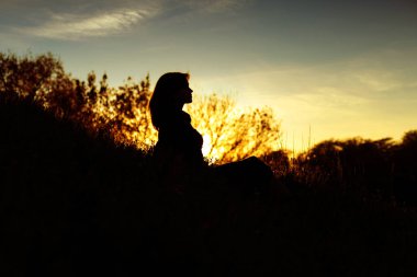 gün batımında bir tepede oturan genç bir kadının silueti, sonbahar manzara kız figürü