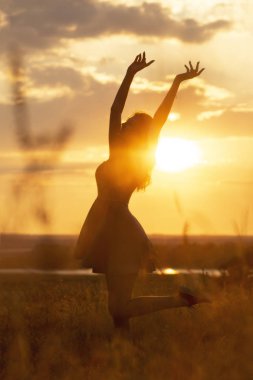 bir alanda gün batımında güzel bir rüya kız silueti, genç bir kadın doğa üzerinde mutluluk ile idance