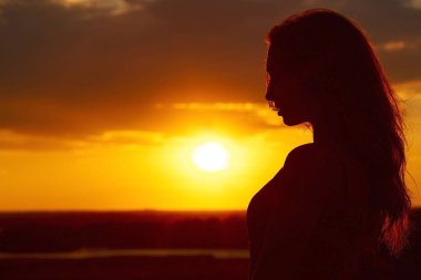 gün batımında güzel bir romantik kız silueti , sıcak havalarda uzun saçlı genç kadının yüz profili