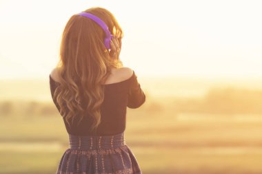 alanında gün batımında doğada müzik dinlerken kulaklık kız