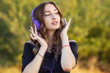 kulaklıkbir müzik sever genç kız portresi, genç kadın alanında doğa güzel şarkı dinlerken