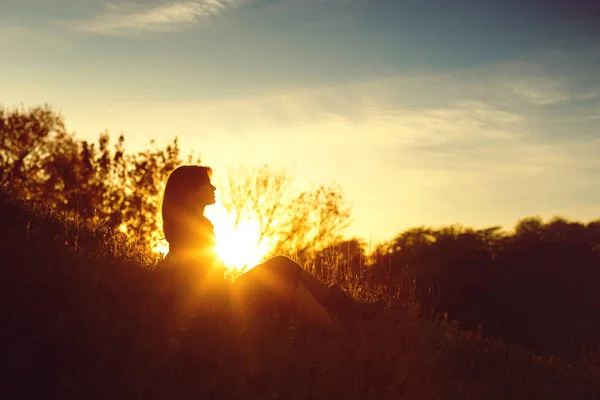 秋の夕日の丘の上に座っている若い女性のシルエット、人間と自然の概念 — ストック写真