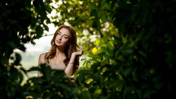 夏の庭で美しい笑顔の女の子の肖像画、緑の葉の若い女性 — ストック写真