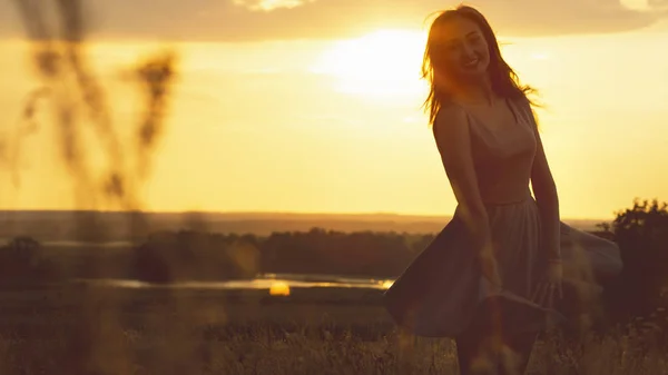 在日落的田野中，一个梦幻般的女孩的剪影，一个年轻女子享受自然 — 图库照片