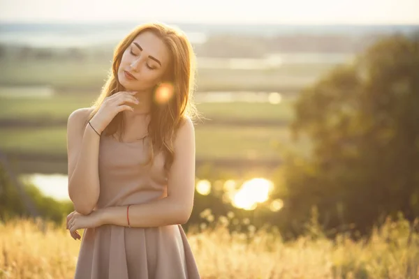 Retrato de uma menina sonhadora em um campo ao pôr do sol, uma jovem mulher desfrutando da natureza — Fotografia de Stock