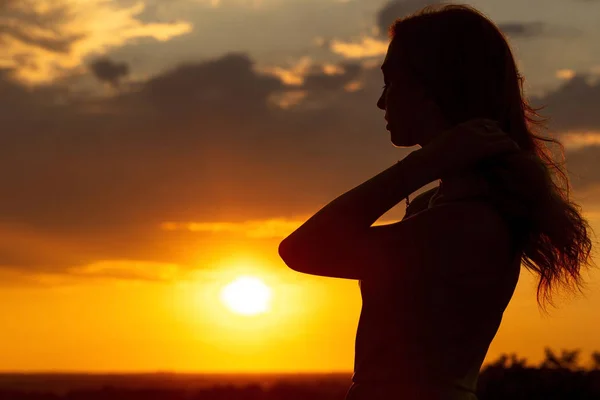 Silueta de una hermosa chica romántica al atardecer, perfil facial de mujer joven con cabello largo en clima cálido —  Fotos de Stock