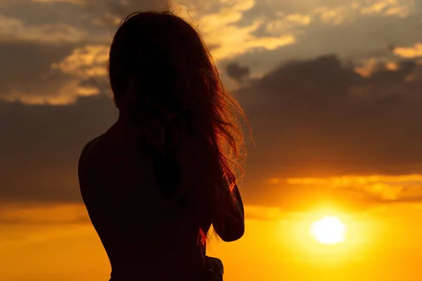 Sziluettje egy gyönyörű romantikus lány naplementekor, arc profilja a fiatal nő, hosszú hajú, meleg időjárás — Stock Fotó