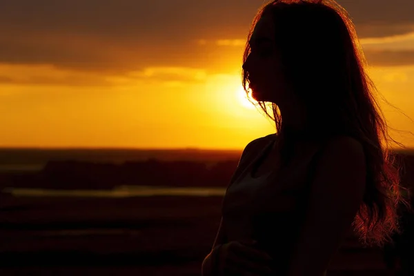 Silhouette eines schönen romantischen Mädchens bei Sonnenuntergang, Gesichtsprofil einer jungen Frau mit langen Haaren bei heißem Wetter — Stockfoto