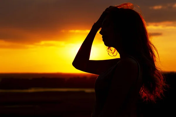 Silhouette eines schönen Mädchens bei Sonnenuntergang auf einem Feld, Gesichtsprofil einer jungen Frau, die die Natur genießt — Stockfoto