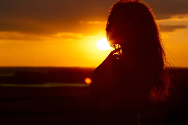 Silhouette eines schönen Mädchens bei Sonnenuntergang auf einem Feld, Gesichtsprofil einer jungen Frau, die die Natur genießt — Stockfoto