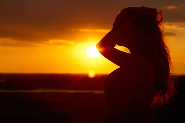 Silhueta de uma menina bonita ao pôr do sol em um campo, perfil de rosto de jovem apreciando a natureza — Fotografia de Stock