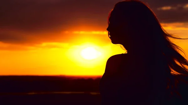 Silhouette d'une belle fille au coucher du soleil dans un champ, profil visage de jeune femme — Photo