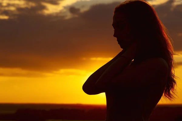 Silueta de una hermosa chica romántica al atardecer, perfil facial de mujer joven con cabello largo en clima cálido —  Fotos de Stock