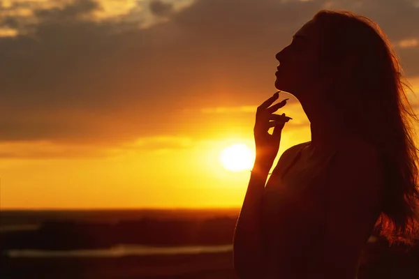 Silhouette d'une belle fille au coucher du soleil dans un champ, profil visage de jeune femme sur la nature — Photo