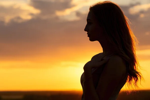 Silhouette di una bella ragazza romantica al tramonto, profilo viso di giovane donna con i capelli lunghi in tempo caldo — Foto Stock