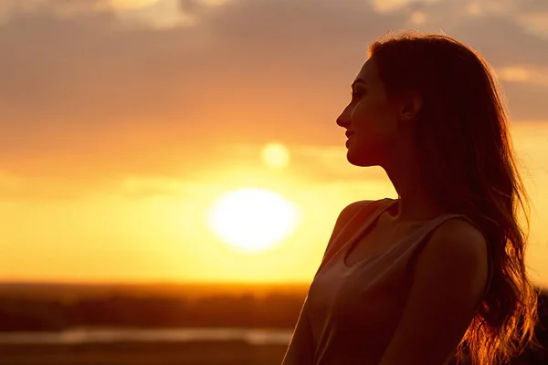 Silhouette di una bella ragazza al tramonto in un campo, profilo volto di giovane donna godendo la natura — Foto Stock