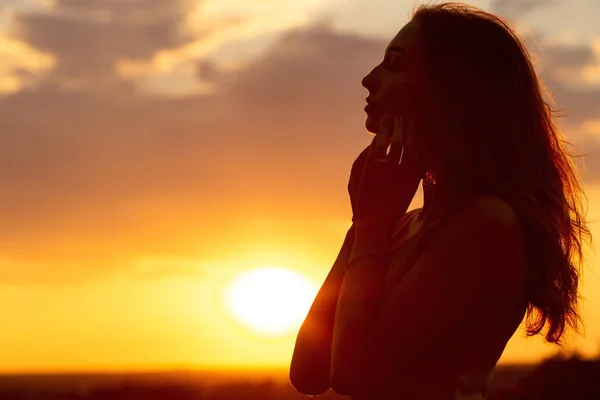 Silhouette di una bella ragazza romantica al tramonto, profilo viso di giovane donna con i capelli lunghi in tempo caldo — Foto Stock
