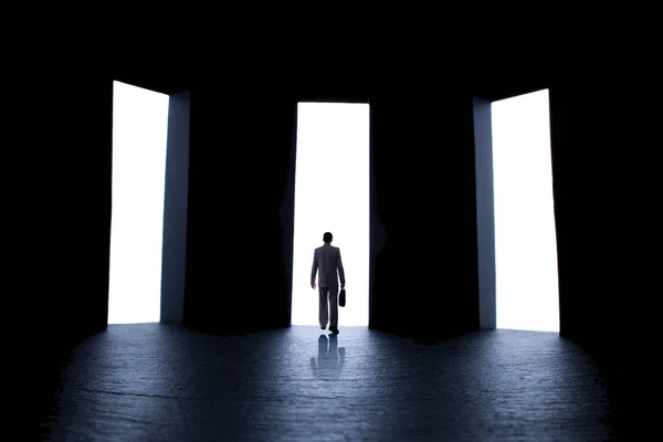 Silhouette of a young man in a business suit with a briefcase in front of three open doors, person decides what path to choose, the concept of life choices and business — Stock Photo, Image