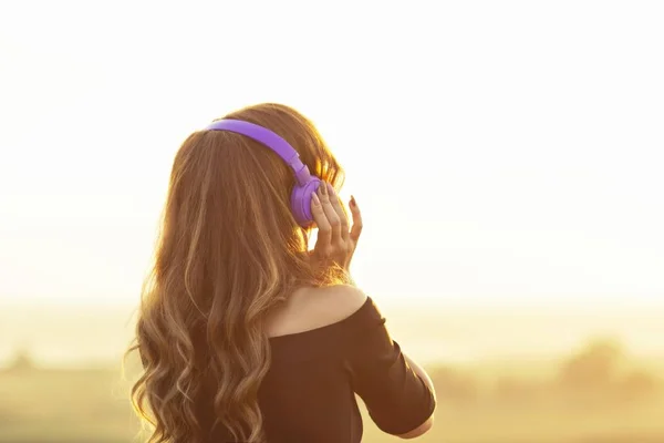 Έφηβος κορίτσι στα ακουστικά ακούγοντας μουσική στη φύση, νεαρή γυναίκα είναι χαλαρωτικό και κοιτάζοντας το ηλιοβασίλεμα στο γήπεδο του καλοκαιριού, — Φωτογραφία Αρχείου