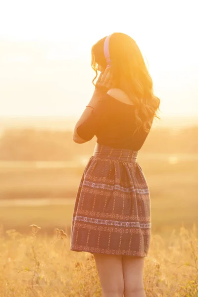 フィールドの夕日に自然の音楽を聴くヘッドフォンの女の子 — ストック写真
