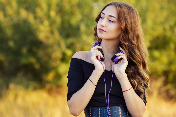 Porträtt av en musikälskare tonåring flicka i hörlurar, ung kvinna lyssnar på härlig sång på naturen i fält — Stockfoto