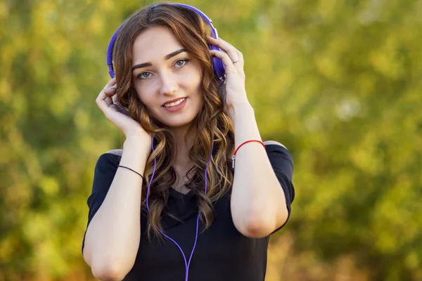 Porträtt av en musikälskare tonåring flicka i hörlurar, ung kvinna lyssnar på härlig sång på naturen i fält — Stockfoto
