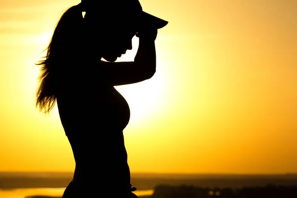 Silueta de una mujer cansada después de correr al atardecer, una niña limpia el sudor de la cara, el deporte conceptual y el cuidado de la salud —  Fotos de Stock