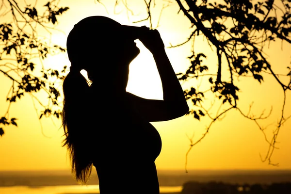 Silhouette einer Frau in Mütze mit guter Laune bei Sonnenuntergang, Konzeptsport, Erholung und Gesundheit — Stockfoto