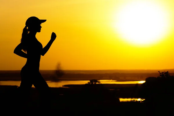 Silueta de una mujer corriendo sobre la naturaleza al atardecer, perfil de chica deportiva, concepto de deporte y ocio —  Fotos de Stock