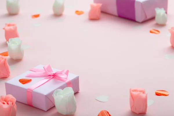 Achtergrond van geschenken met confetti harten en rozen, dozen verpakt in decoratief papier op Pastel gekleurde roze achtergrond, vakantie concept en liefde — Stockfoto
