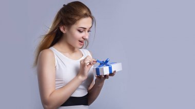 mutlu kadın bir stüdyo arka plan üzerinde hediye kutusu açılış, kız untying mavi kurdele yay ve merak, konsept tatil ve mucizeler