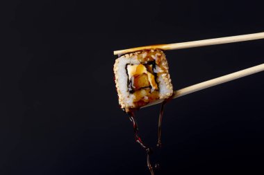 siyah arka plan üzerinde çubukları arasında lezzetli rulo, suşi damlaso soya sosu damlaları, gıda arka plan, Japon mutfağı