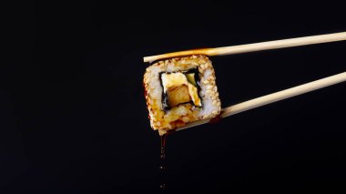 siyah arka plan üzerinde çubukları arasında lezzetli rulo, suşi damlaso soya sosu damlaları, gıda arka plan, Japon mutfağı