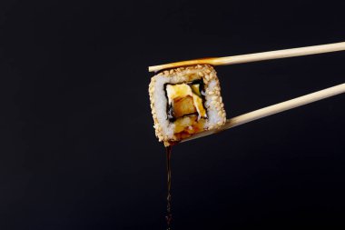 siyah arka plan üzerinde çubukları arasında lezzetli rulo, suşi damlaso soya sosu damlaları, gıda arka plan, Japon mutfağı