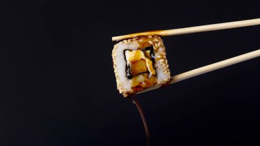 siyah arka plan üzerinde çubukları arasında lezzetli rulo, suşi damlaso soya sosu damlaları, gıda arka plan, Japon mutfağı