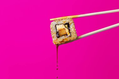 renkli bir arka plan üzerinde çubukları arasında lezzetli rulo, suşi damlaso sosu damlaları, gıda arka plan, Japon mutfağı