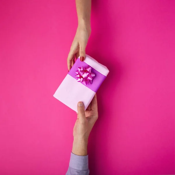 Homem dá uma menina um presente de mão em mão, caixa envolta em papel decorativo com um fundo de arco, o conceito de feriados, amor e relacionamentos, vista superior — Fotografia de Stock