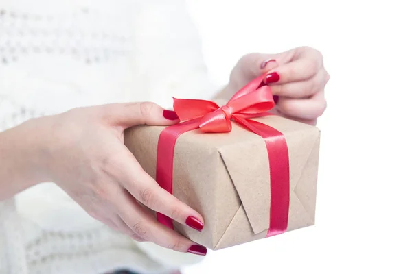 Menina segurando um presente em mãos, mulher abrindo a caixa envolto em papel artesanal no fundo isolado branco, conceito férias de inverno — Fotografia de Stock