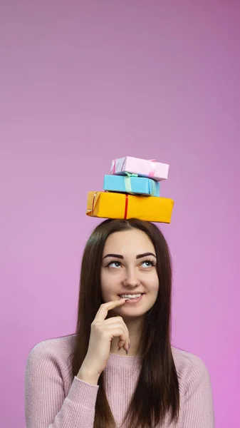 Портрет счастливой девушки куча подарочных коробок на голове, улыбающаяся молодая женщина представляет с пальцем у рта подарки, концепция праздники и эмоции — стоковое фото