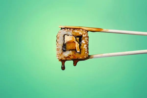 succulent roll between chopsticks on a colored background, drops