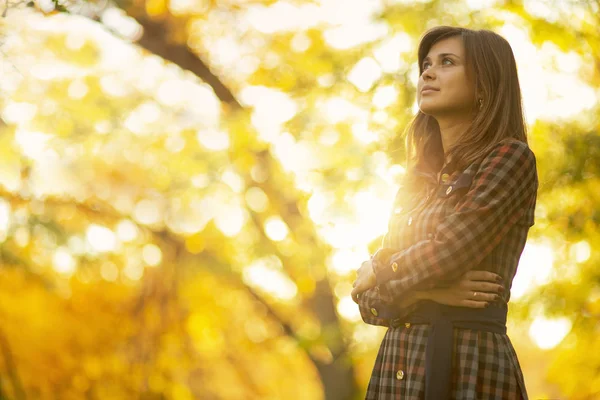 Retrato de uma menina bonita em um vestido andando na natureza no outono, uma jovem mulher desfrutando do sol olhando para cima — Fotografia de Stock