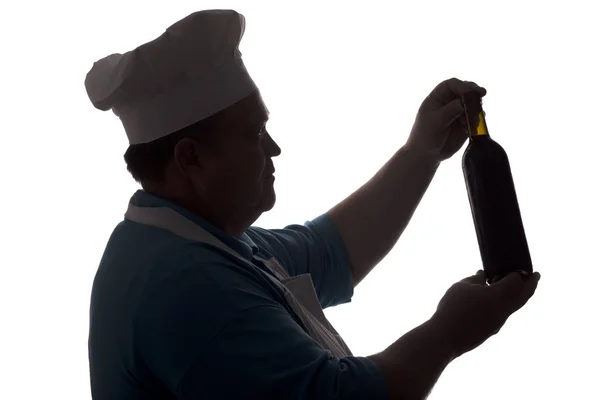 Силует шеф-кухаря, який дивиться на пляшку вина і думає на білому ізольованому фоні, профіль чоловічого обличчя в капелюсі для готування, алкогольний напій — стокове фото