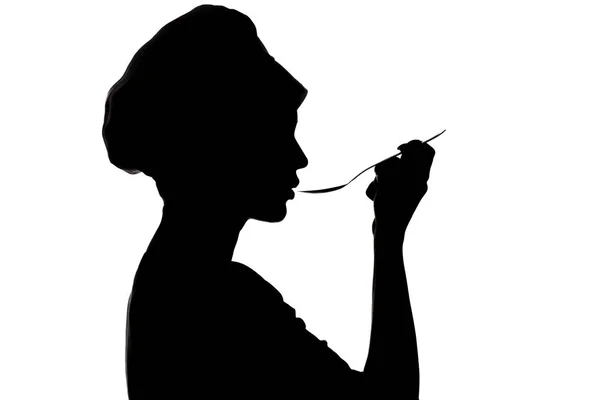 Silhouette de femme cuisinant dans une casquette, profil d'une fille soufflant à la soupe sur une cuillère sur un fond blanc isolé — Photo