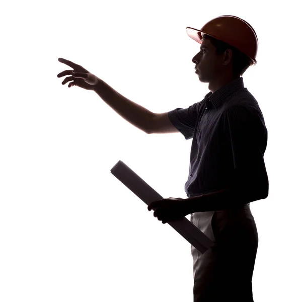 Силуэт мужского инженера-строителя со строительным проектом в шлеме дает указания на белом изолированном фоне — стоковое фото