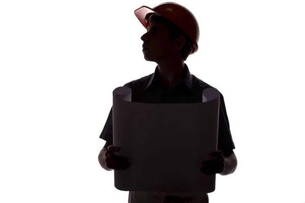 Силуэт инженера-строителя с чертежом здания в шлеме, проверяющего работу на белом изолированном фоне — стоковое фото