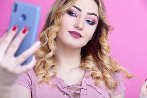 Jovem bela menina posando para uma selfie para uma rede social, um adolescente segura um telefone na mão e sorrindo para a câmera, conceito de estilo de vida juvenil, geração e tecnologia — Fotografia de Stock