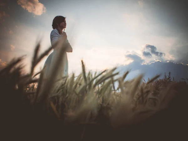 Perfil silueta de una hermosa chica en un vestido en el campo disfrutando del cielo durante el atardecer, una mujer joven caminando en la naturaleza, el concepto de belleza y armonía — Foto de Stock