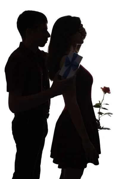Чоловік робить несподіваний сюрприз для своєї коханої жінки, хлопчик пішов позаду і закрив очі дівчинки рукою, щоб дати троянду і подарункову коробку на білому ізольованому тлі, концепція побачень, романтики і l — стокове фото